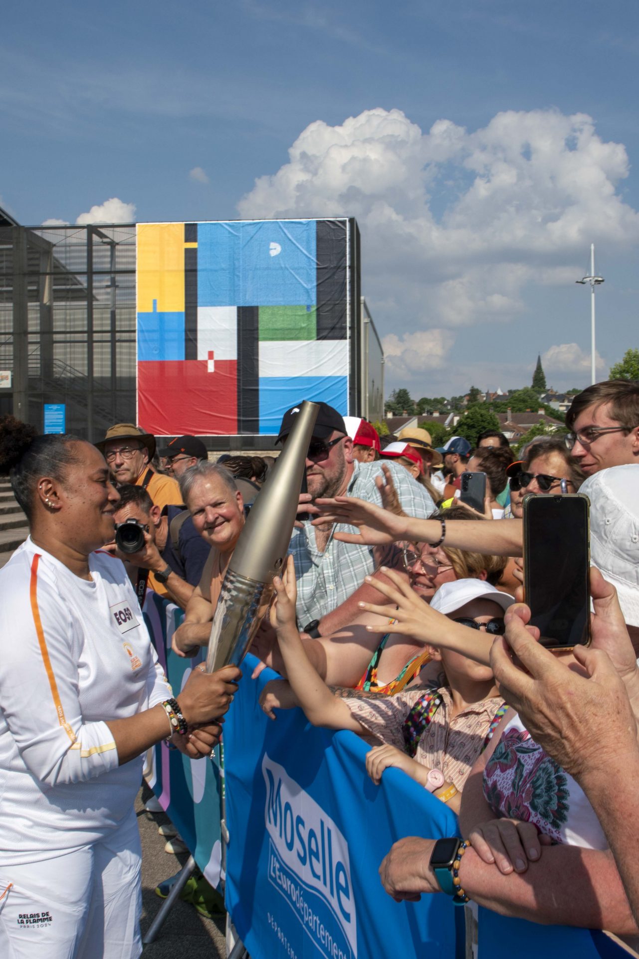 Relais de la flamme olympique &agrave; Metz, foule rassembl&eacute;e et coureurs portant la torche, photographie de Joseph Emile.
